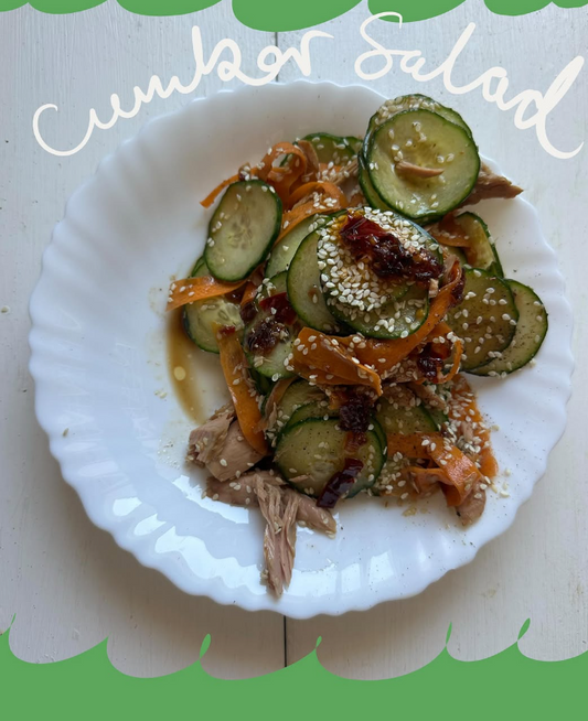 Viral cucumber salad with cucumber, carrot ribbons, tuna and chilli oil dressing on a white plate