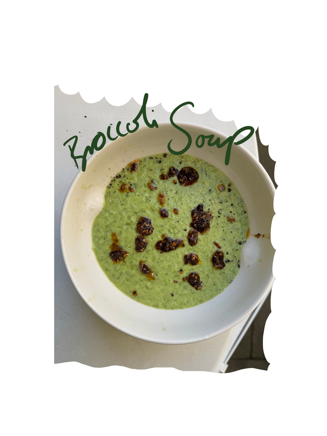Creamy broccoli courgette cheddar soup topped with Chilli Sambal in a white bowl.