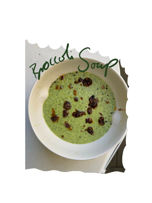 Creamy broccoli courgette cheddar soup topped with Chilli Sambal in a white bowl.